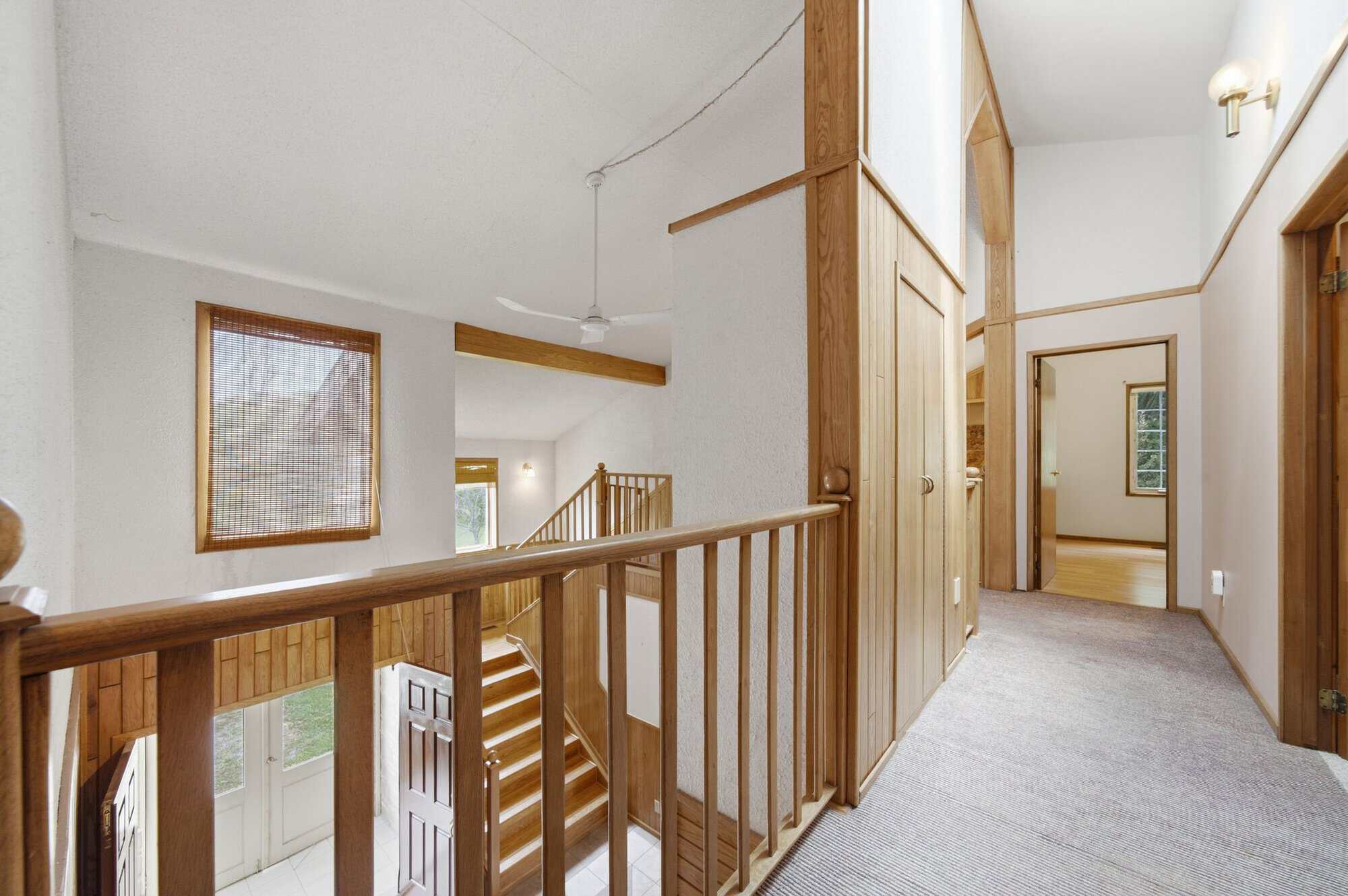 Upper hallway with vaulted ceilings, open railing overlooking the foyer, and bridge-style walkway.