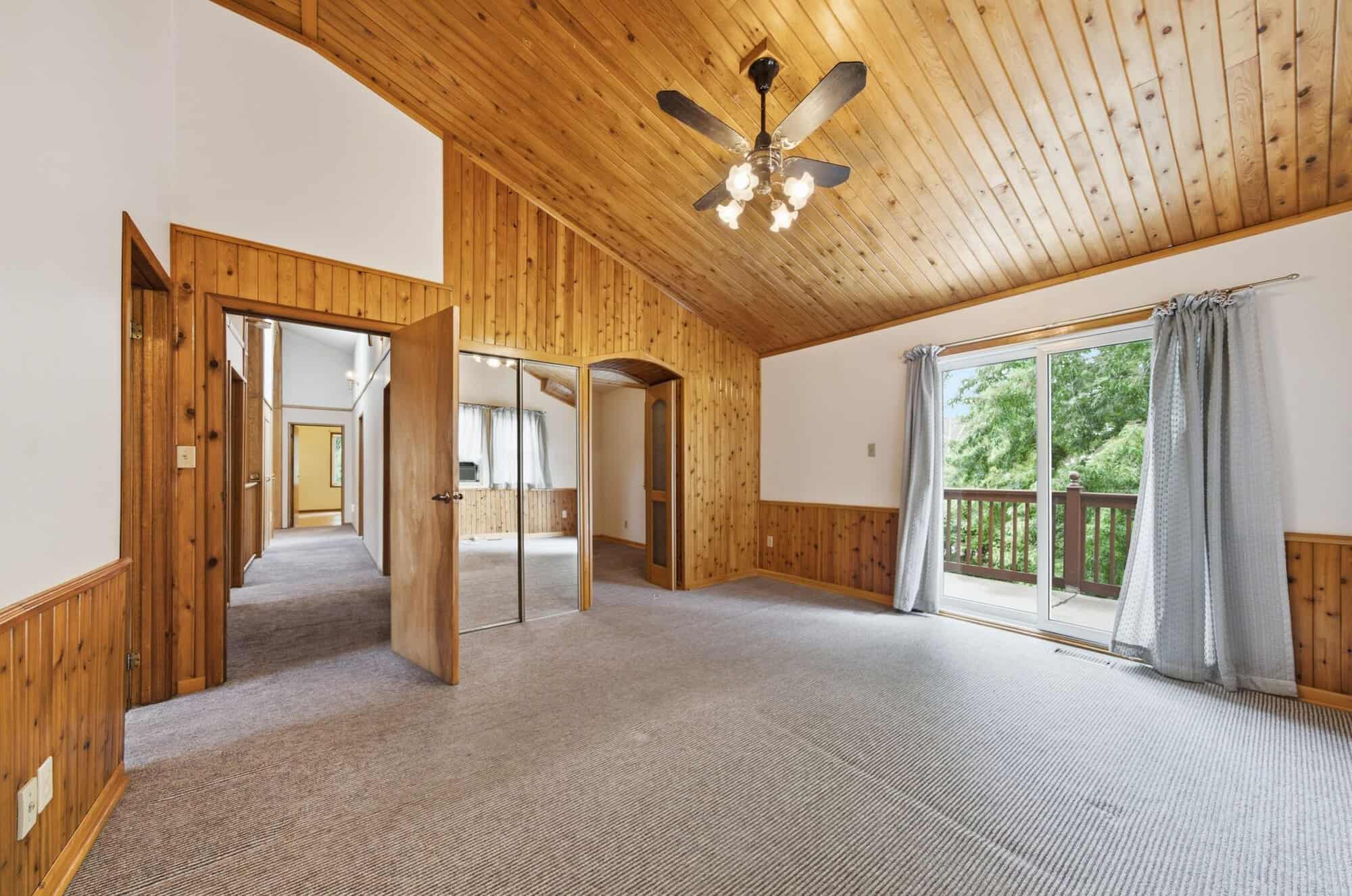 Spacious primary bedroom with vaulted cedar ceiling, private balcony, mirrored closets, and adjoining dressing room.