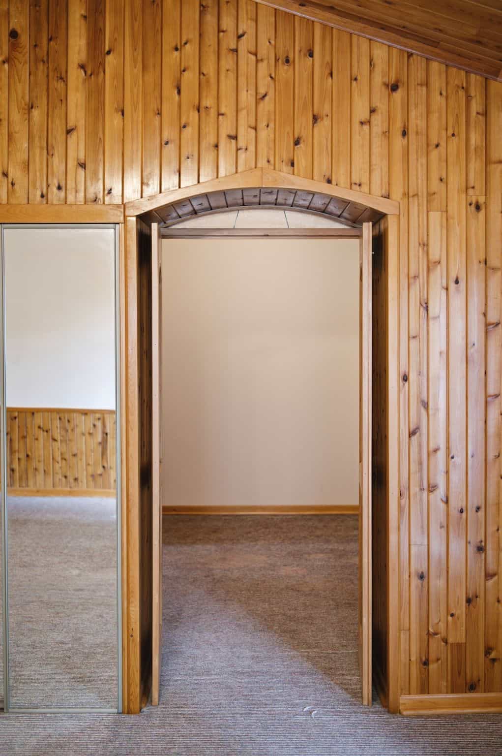 Arched wood doorway leading from the primary bedroom into the private dressing room.