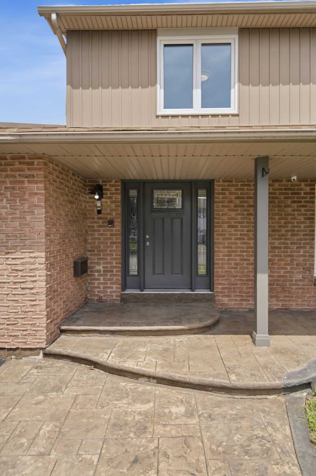 Arched brick front entry at 39 Anstead Crescent in Ajax with a black front door and stone steps.