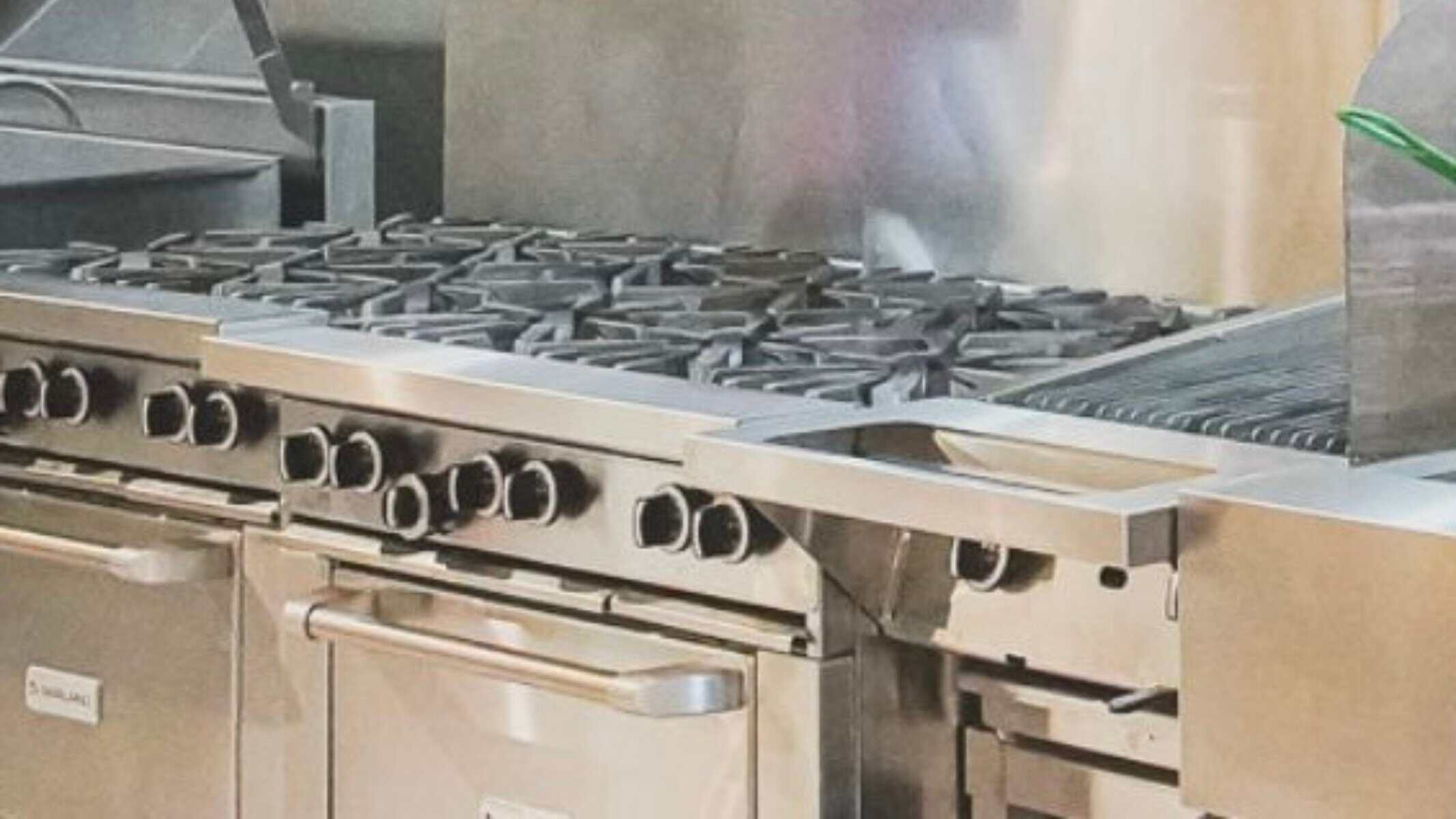“Close-up of a commercial stainless-steel gas range and griddle in the kitchen of a confidential restaurant business for sale.”